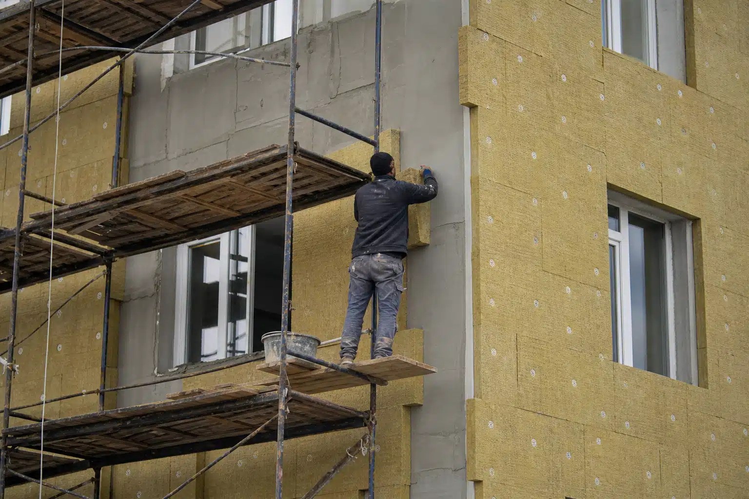 Ouvrier posant panneaux d'isolation thermique sur façade
